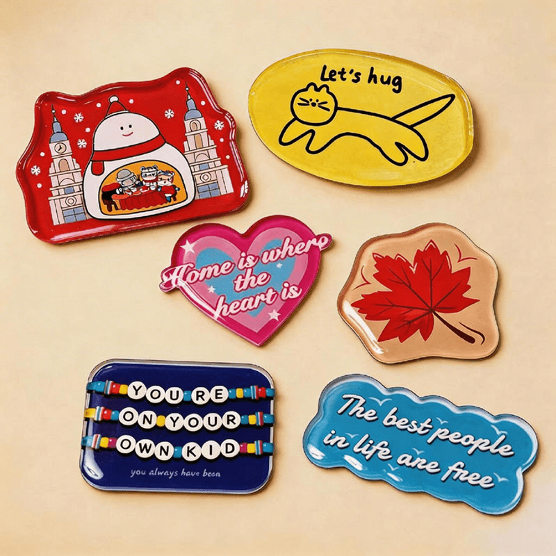Collection of custom acrylic fridge magnets with quotes and illustrations