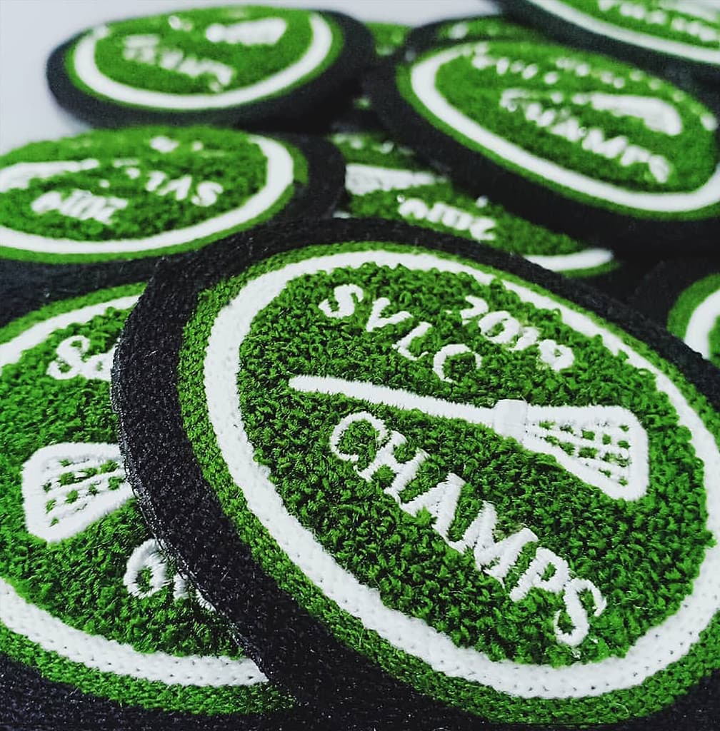 Green and white chenille patches with lacrosse championship lettering