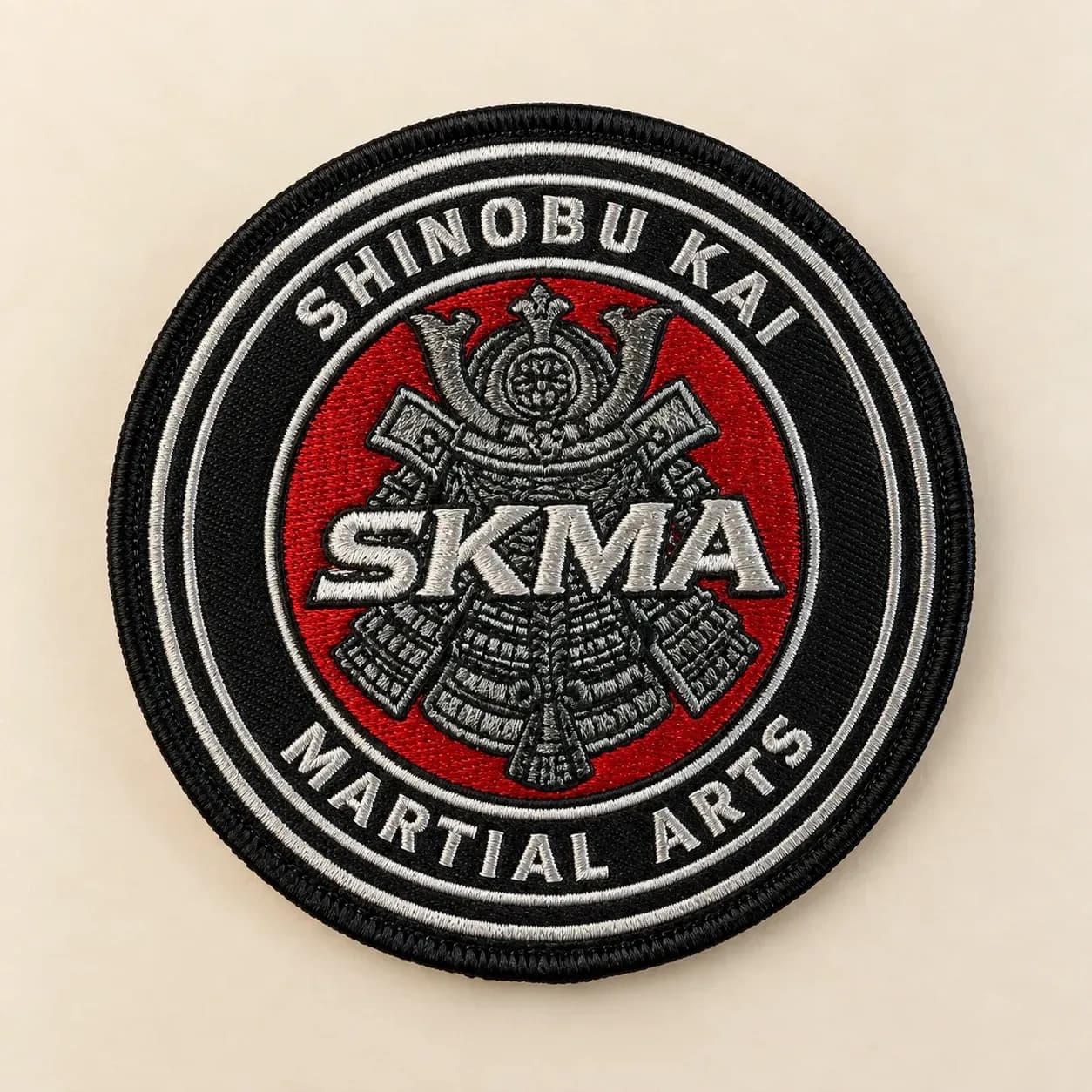 Round black and red embroidered martial arts patch with white lettering