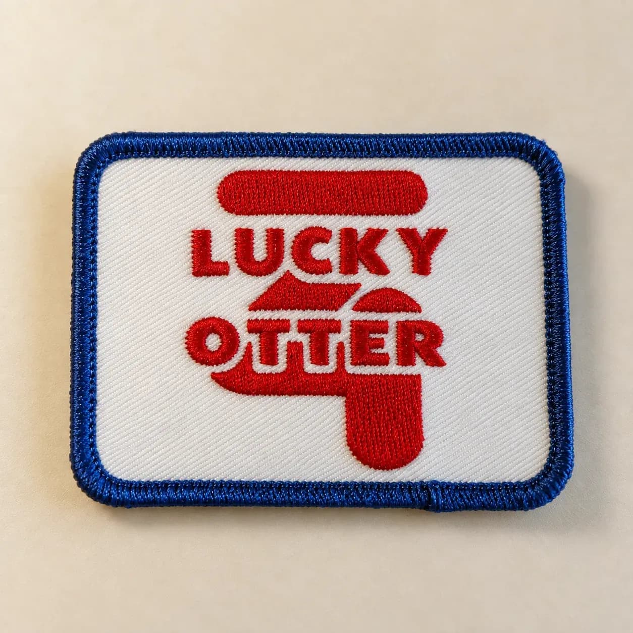 Rectangular Lucky Otter embroidered patch with red lettering and a blue stitched border