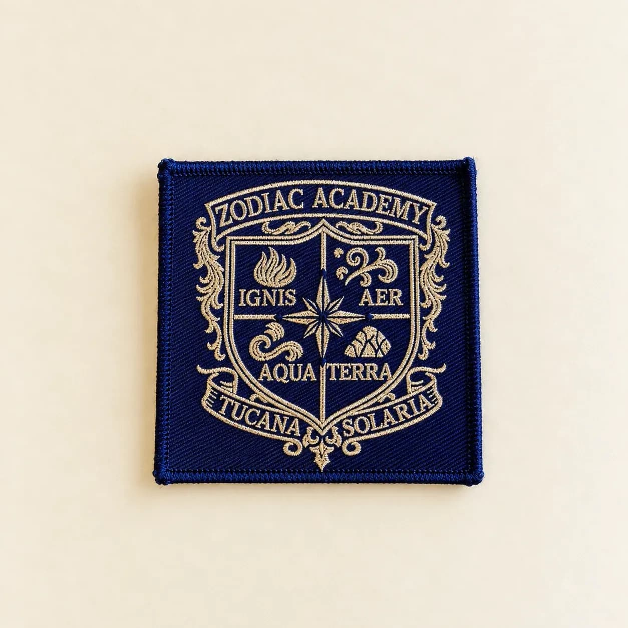 Navy embroidered Zodiac Academy crest with gold lettering and stitched decorative details